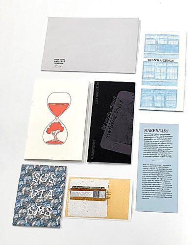 Flat lay of book arts zines and printmaking pamphlets with hourglass art and Makeready card on white background