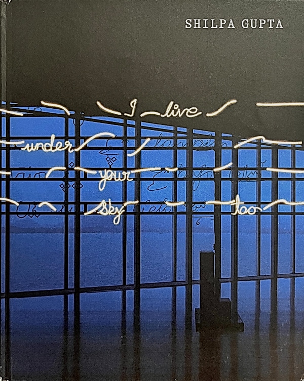 Shilpa Gupta art book cover with neon text 'I live under your sky too' in a blue windowed gallery installation.
